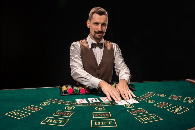 Dealer profesional di meja Three Card Poker idnslot dengan kartu fisik
